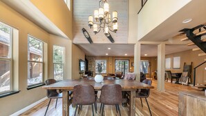 A spacious dining area with a large wooden table, several chairs, and a modern chandelier. - Raven Retreat by Tahoe Getaways- 3 BR at Tahoe Donner w/ Forest Views - HOA Access (Truckee)