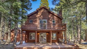 A two-story wooden cabin with a balcony, surrounded by tall pine trees. - Raven Retreat by Tahoe Getaways- 3 BR at Tahoe Donner w/ Forest Views - HOA Access (Truckee)