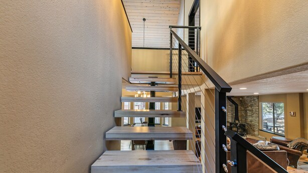A modern staircase with wooden steps and metal railings, leading to a living area with a fireplace and seating. - Raven Retreat by Tahoe Getaways- 3 BR at Tahoe Donner w/ Forest Views - HOA Access (Truckee)