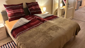 A bed with red and grey striped bedding, a bedside lamp, and a mirror cabinet. - Schlossblick und Komfort in Stolpen (Stolpen)