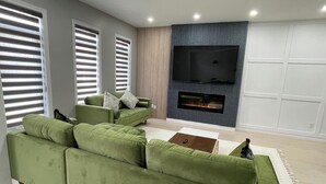 A modern living room with a sectional sofa, a flat-screen TV, and a fireplace.