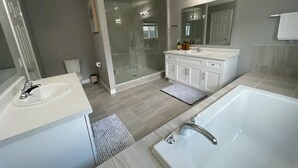 A modern bathroom with a large shower, a bathtub, and a vanity with a mirror.