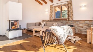 Una sala de estar acogedora con chimenea, vigas de madera, un revestimiento de piedra alrededor de la chimenea, un sofá y un perro.