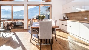 Una cocina moderna con vigas de madera, ventanas amplias y vistas a montañas.