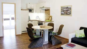 Ett kompakt bostadsutrymme med kök, matplats och sittgrupp.