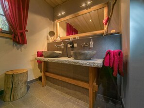 Une salle de bain avec un lavabo en pierre, un meuble-lavabo en bois et un miroir au-dessus.