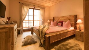 A cozy bedroom with a wooden bed, a dresser, a window with curtains, and a fur rug on the floor. - Castle Chalet No. 19 (Ilsenburg)