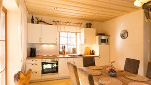 A cozy kitchen with wooden cabinets, a built-in oven, and a dining area with a wooden table and chairs. - Castle Chalet No. 19 (Ilsenburg)