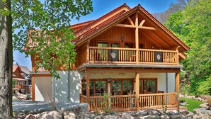 A wooden chalet with a balcony, large windows, and a stone foundation. - Castle Chalet No. 19 (Ilsenburg)