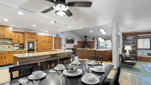 A modern kitchen with wooden cabinets, a central island, and a dining area set for six.