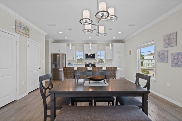 A spacious dining area with a dark wooden table and chairs, a central island with a fire feature, and a modern chandelier.