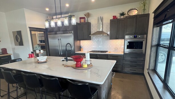 A modern kitchen with a large island, dark cabinetry, stainless steel appliances, and pendant lighting. - Cozy retreat located in the perfect location for views of the mountains and lake (Eagle Nest)