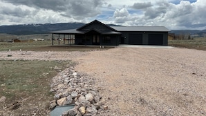 A large, dark-colored building with a covered porch and a gravel driveway. - Cozy retreat located in the perfect location for views of the mountains and lake (Eagle Nest)