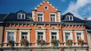 A red brick building with white trim, multiple windows, and flower boxes on the second floor. - Cosy Apartment in Eibenstock (Eibenstock)