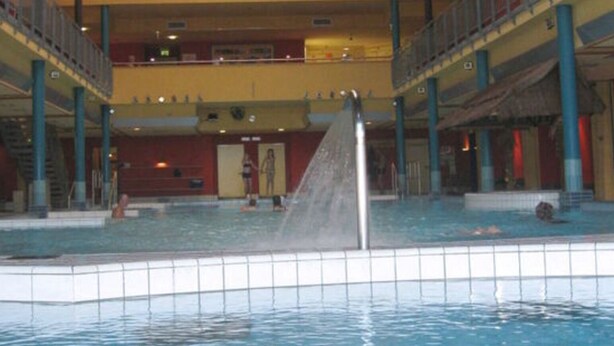 An indoor swimming pool with a high ceiling and a central water slide. - Cosy Apartment in Eibenstock (Eibenstock)