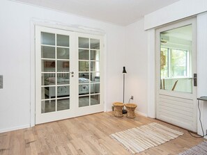 A room with a wooden floor, a white door with glass panels, a standing lamp, and a woven floor mat. - 8 Person Holiday Home in Nordborg (Nordborg)