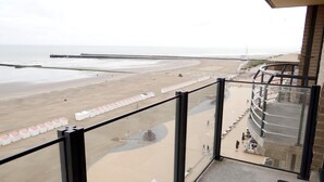 Un balcon avec vue sur une plage et une jetée.