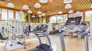 Une salle de sport équipée de tapis de course, de vélos elliptiques et d’appareils de musculation.