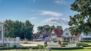 A park with benches, a fountain, and a variety of trees. - Residence Starfish Comfortable Vacation Home (Boltenhagen)