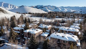 Quartiere residenziale con case innevate e montagne sullo sfondo.
