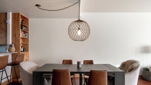 Zona pranzo con tavolo in legno, sei sedie e lampadario.