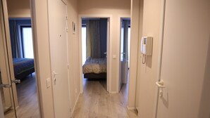 En hotellkorridor med ett trägolv, en säng med ett mönstrat överkast och en telefon på väggen.
