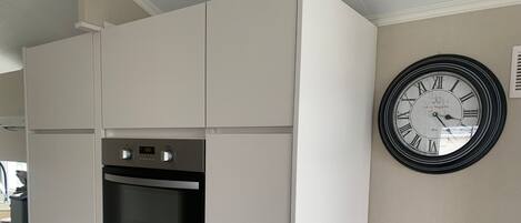 A kitchen with white cabinets, a built-in oven, and a wall clock.