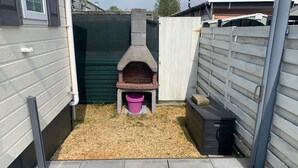 A small outdoor area with a stone oven, a wooden bench, and a trash bin. - Wonderful Holiday Home in Nieuwpoort Near Dunepark (Nieuwpoort)