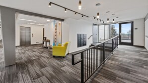 Un interior moderno con un sillón amarillo, una escalera y vistas al exterior.
