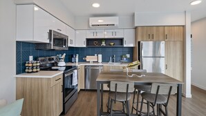 Una cocina moderna con alacenas blancas, un refrigerador de acero inoxidable, un microondas y un lavavajillas.