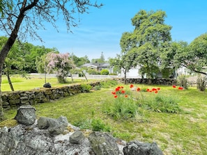 A garden with a stone wall, a white building, and a clear sky. - 4 Person Holiday Home in Farjestaden (Farjestaden)