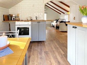A kitchen with white cabinets, a wooden countertop, and a dining area with a table and chairs. - 4 Person Holiday Home in Farjestaden (Farjestaden)