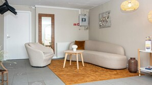 Una sala de estar moderna con un sofá color beige, una mesita redonda de madera y una alfombra marrón.