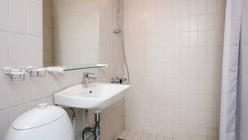 A bathroom with a white sink, a glass shelf, a shower, and a toilet.