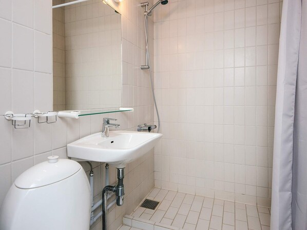 A bathroom with a white sink, a glass shelf, a shower, and a toilet. - 3 Person Holiday Park Home in Ulfborg (Ulfborg)