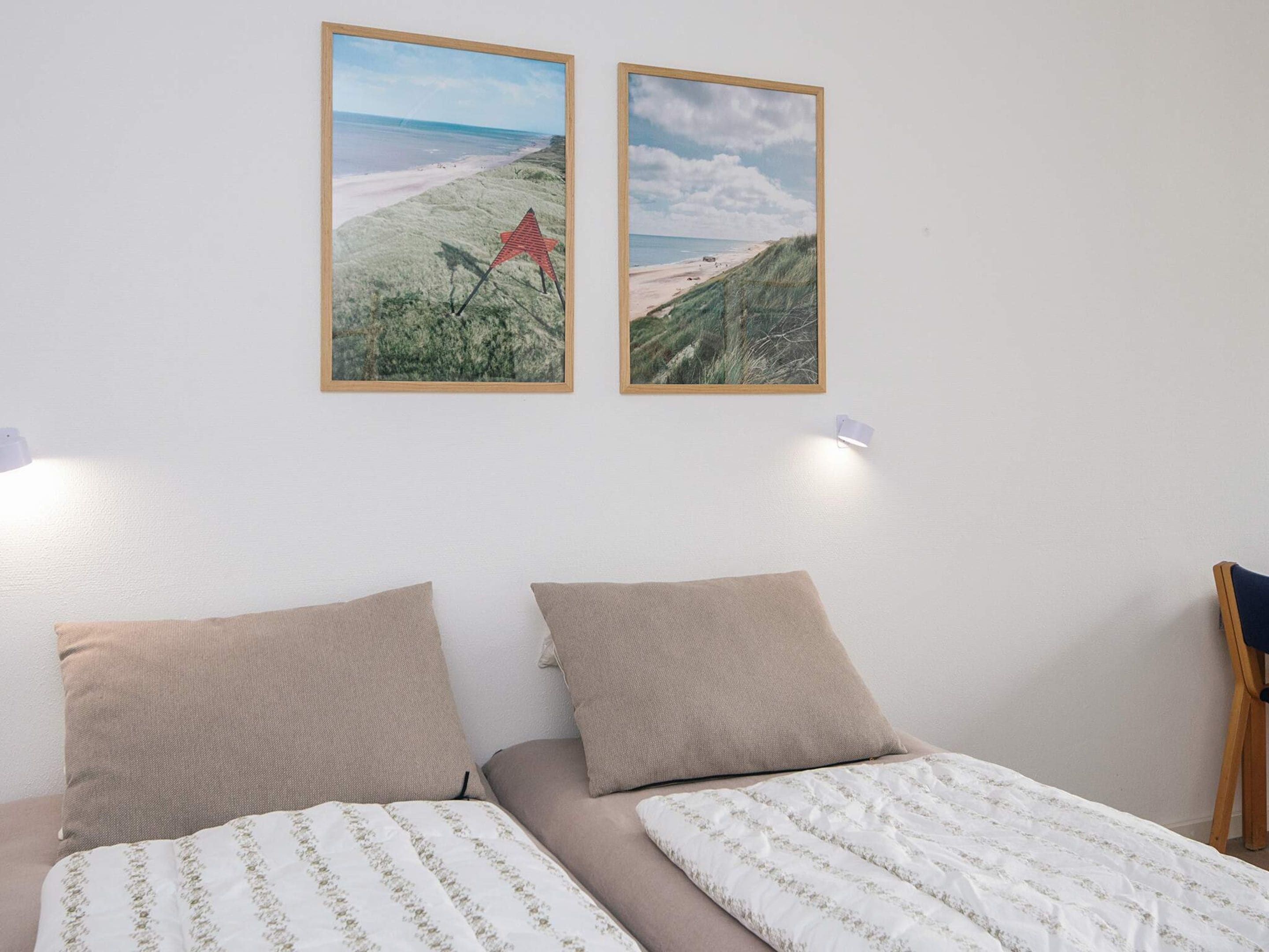 Un dormitorio con dos camas, vista a la playa y dos cuadros en la pared.