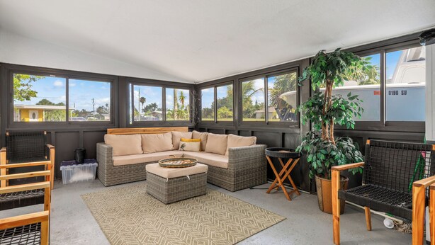 A sunroom with a large window, wicker furniture, a potted plant, and a view of the outside. - Relax N Rentals Waterfront 4BR 2BA Port Charlotte FL Pool Kayaks Harbor Access (Port Charlotte)