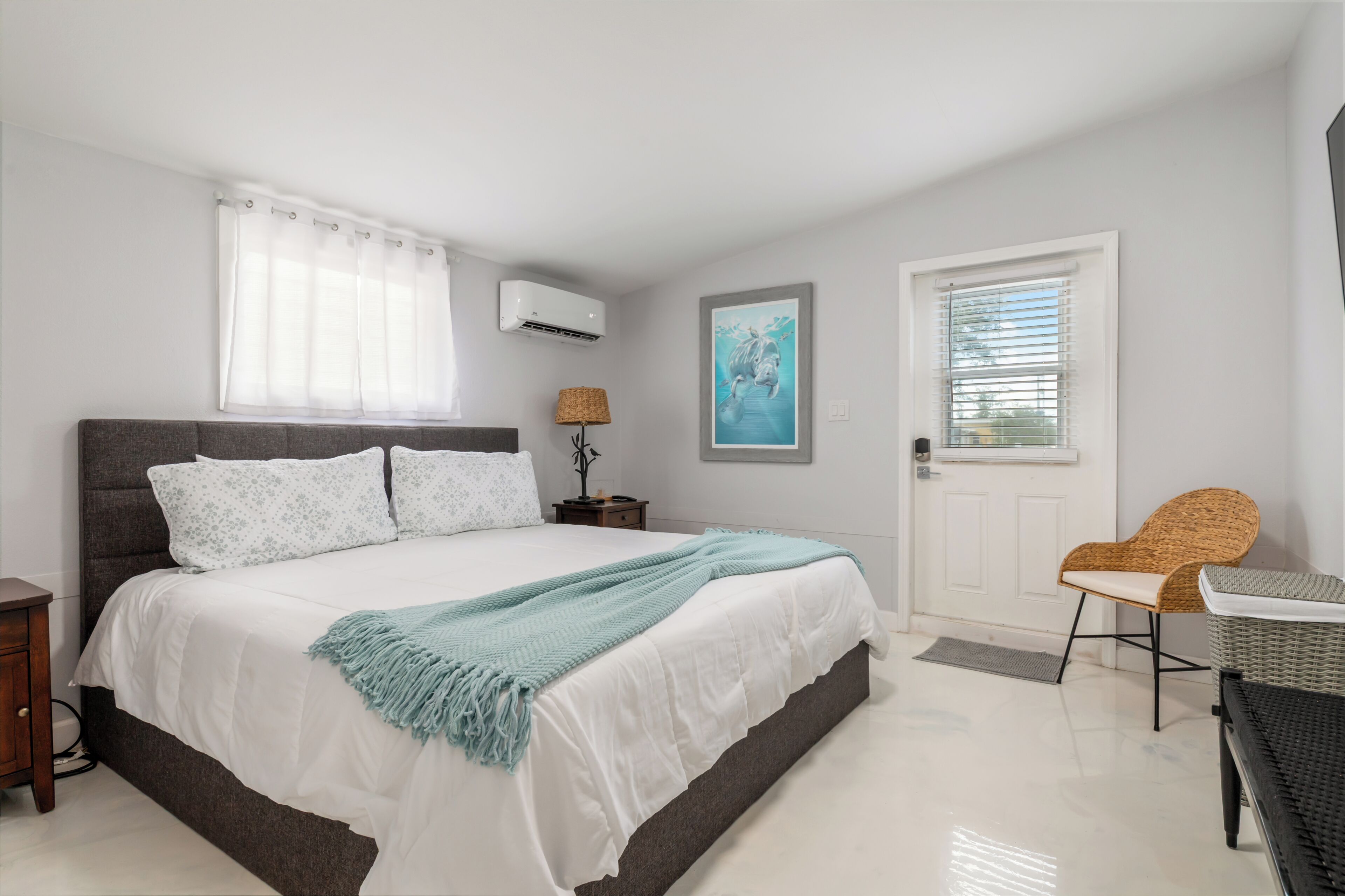 A bedroom with a bed, bedside table, lamp, and a door.