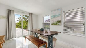 A dining area with a wooden table, bench, and two chairs. There is a window with blinds, a painting on the wall, and a sign on the curtain rod. - Relax N Rentals Waterfront 4BR 2BA Port Charlotte FL Pool Kayaks Harbor Access (Port Charlotte)