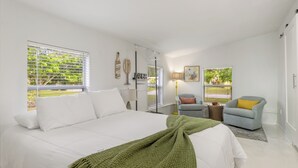 A bedroom with a bed, a chair, a lamp, and a window with blinds. - Relax N Rentals Waterfront 4BR 2BA Port Charlotte FL Pool Kayaks Harbor Access (Port Charlotte)