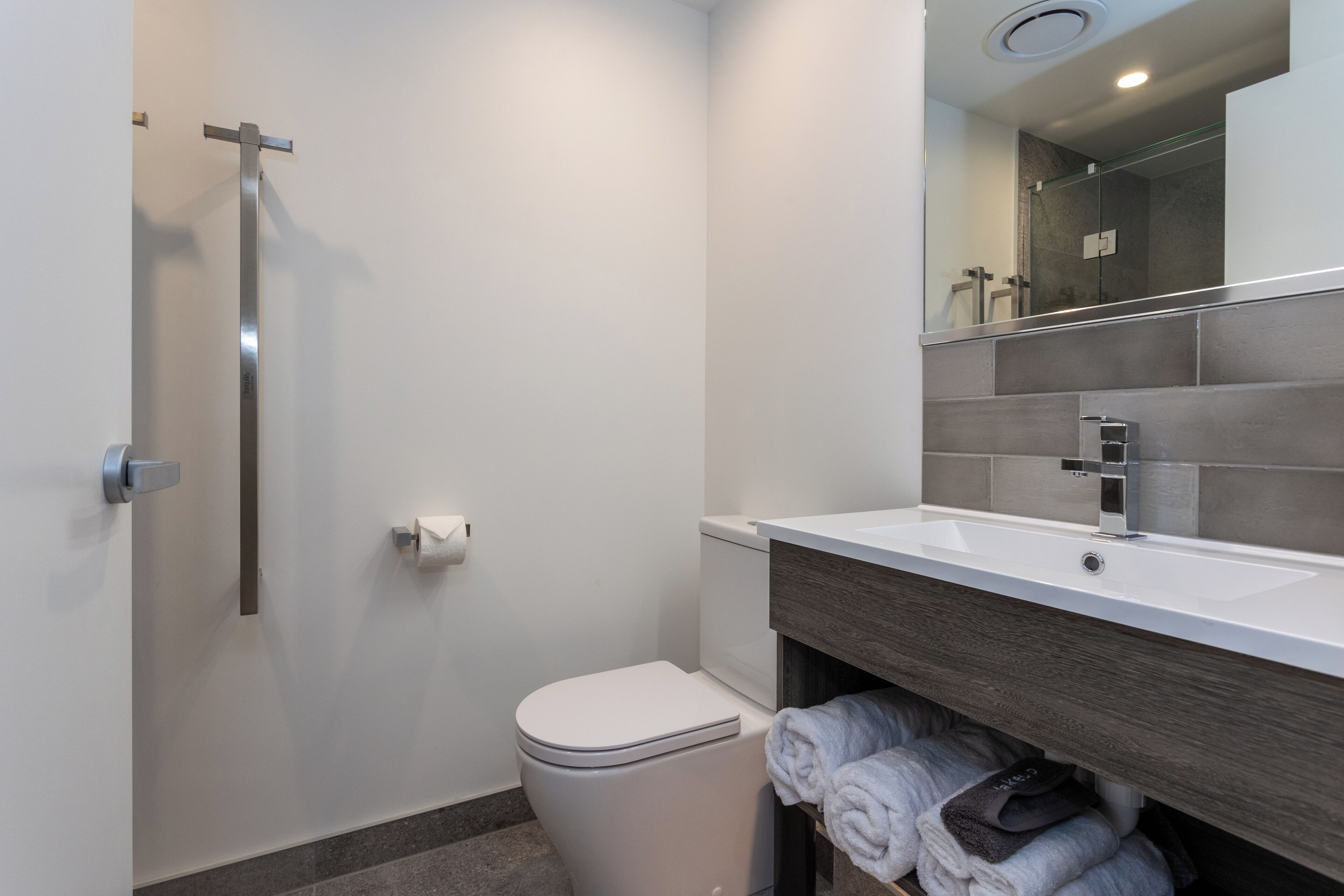 A modern bathroom with a toilet, a sink, and a shower.