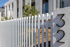 A white fence with the numbers '32' on a textured wall. - Arluxia (Auckland)