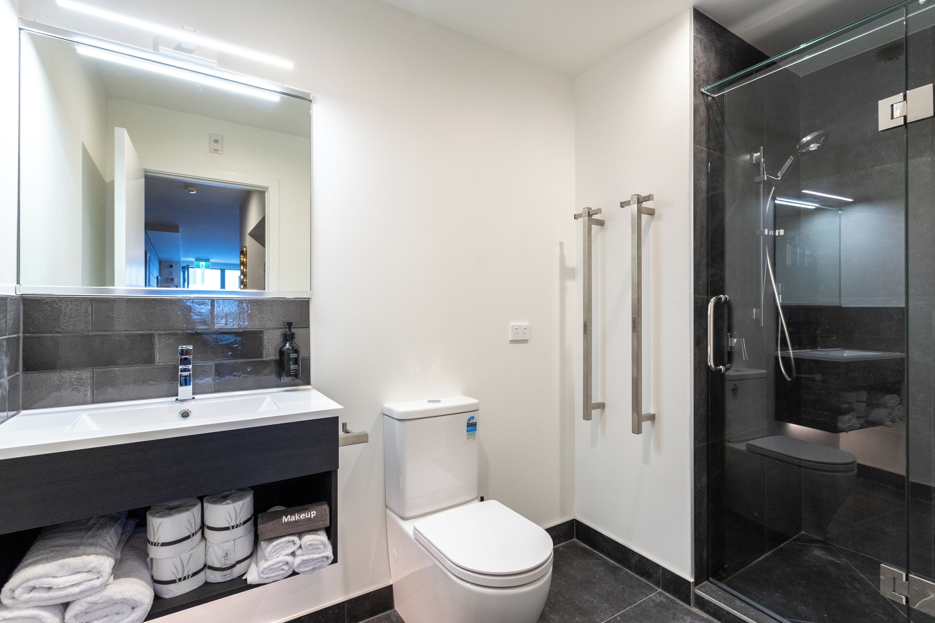 A modern bathroom with a white sink, toilet, and glass-enclosed shower.