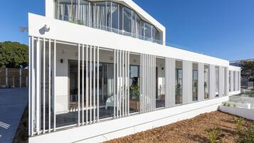Un edificio moderno con fachada blanca, ventanas grandes y un balcón con plantas.