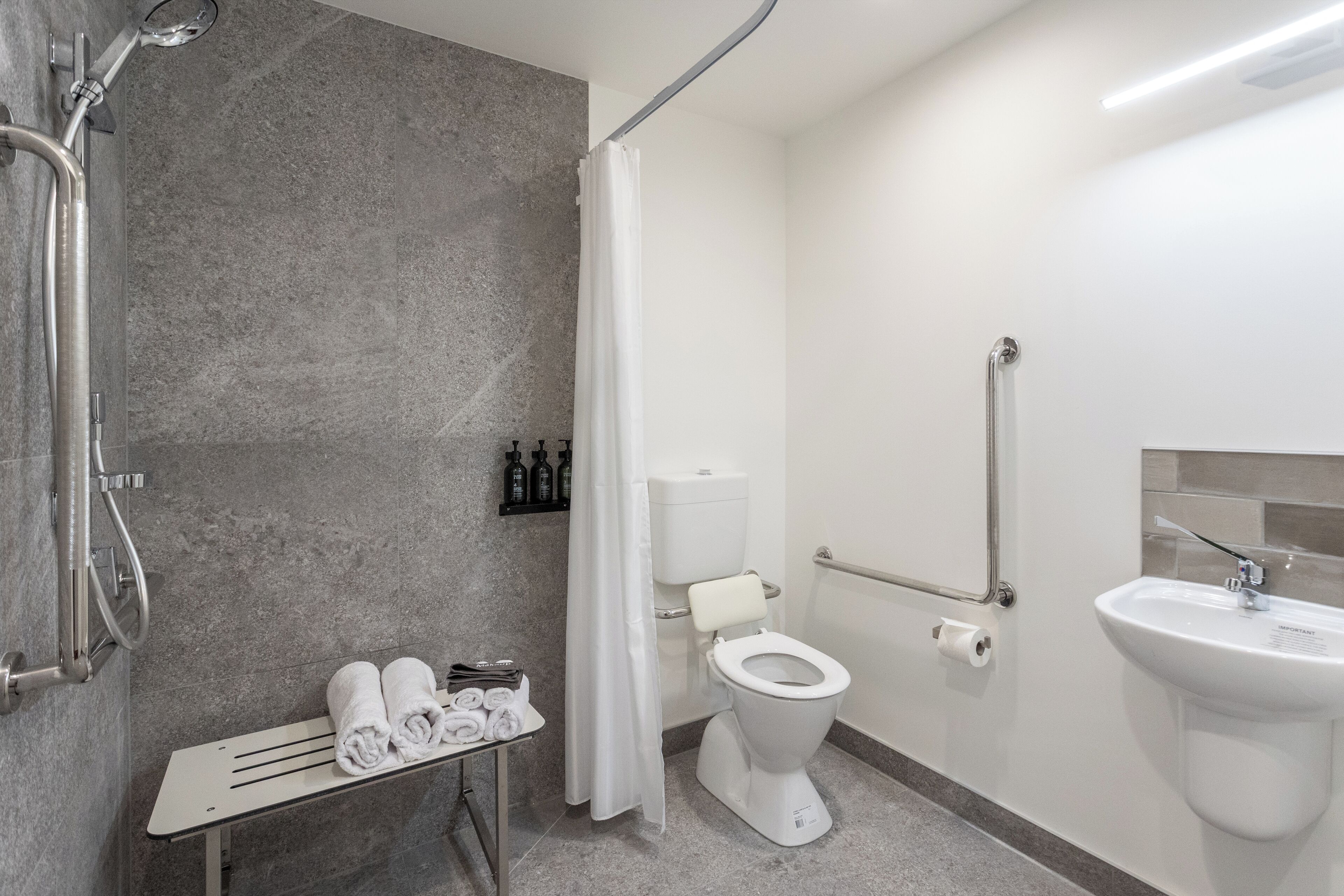 A modern bathroom with a shower, toilet, and sink.