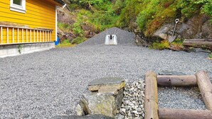A yellow building with a gravel path leading to a rocky area. - 8 Person Holiday Home in Masfjordnes (Masfjorden)