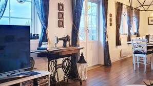 A cozy living room with a sewing machine, a TV, and a dining area with a table and chairs. - 8 Person Holiday Home in Masfjordnes (Masfjorden)