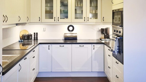 A modern kitchen with white cabinets, a black countertop, and stainless steel appliances. - 8 Person Holiday Home in Masfjordnes (Masfjorden)