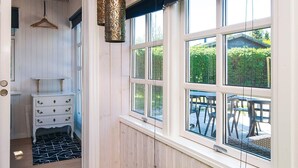 A room with a bed, a dresser, a hanging light fixture, and large windows with a view of the outdoors. - 4 Star Holiday Home in Grenaa (Grenaa)