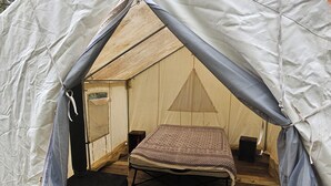 Une tente équipée d’un lit, d’une petite table et d’enceintes.